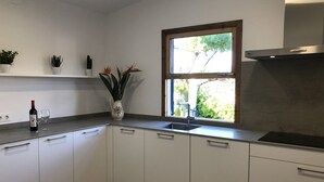 A modern kitchen with white cabinets, a stainless steel sink, and a window with a view of greenery outside. - Villa ideal for families with pool and bbq near the sea in Pollença and WIFI (Pollença)