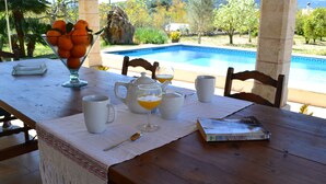 A dining table with a glass bowl of oranges, white cups, a teapot, and a book titled "The Telophorus Admirals". - Villa ideal for families with pool and bbq near the sea in Pollença and WIFI (Pollença)