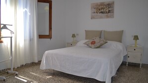 A bedroom with a bed, two bedside tables, a mirror, and a painting on the wall. - Villa ideal for families with pool and bbq near the sea in Pollença and WIFI (Pollença)