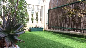Ein gepflegter Garten mit Kunstgrasanlage, verschiedenen Pflanzen und einem Bambuszaun.