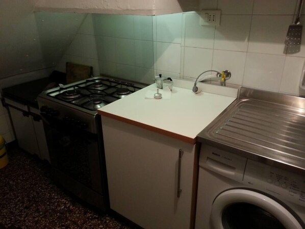 A compact kitchen with a gas stove, a sink, and a washing machine. - GIVE A HOLIDAY IN ONE OF THE MOST BEAUTIFUL PLACES OF LIGURIA (Sestri Levante)
