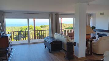 A spacious balcony with a view of a forested landscape.