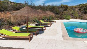 A poolside area with lounge chairs and a thatched structure. - Casa do Cabeço das Águias, 2 km from the beach and 35 km from Lisbon (Aldeia do Meco)