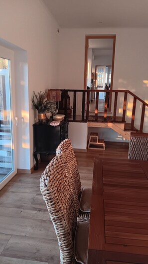 A spacious living area with a wooden staircase, a black console table, and a woven chair. - Casa do Cabeço das Águias, 2 km from the beach and 35 km from Lisbon (Aldeia do Meco)