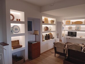 A well-lit room with shelves displaying various decorative items, a wooden chest, and a television. - Casa do Cabeço das Águias, 2 km from the beach and 35 km from Lisbon (Aldeia do Meco)