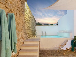 Un muro di pietra, una piscina e una sedia.