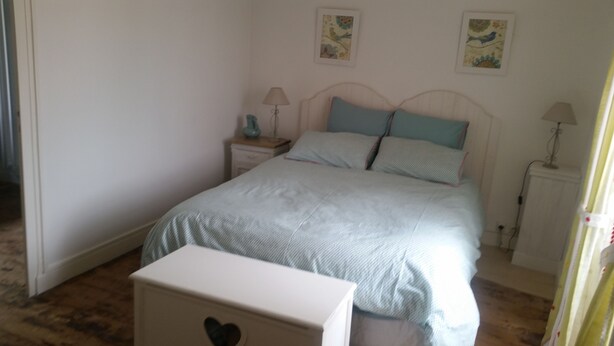 A bedroom with a bed, bedside tables, lamps, and artwork on the walls.