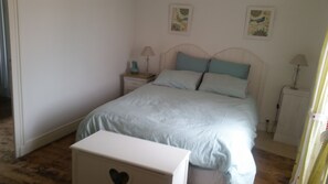 A bedroom with a bed, bedside tables, lamps, and artwork on the walls.