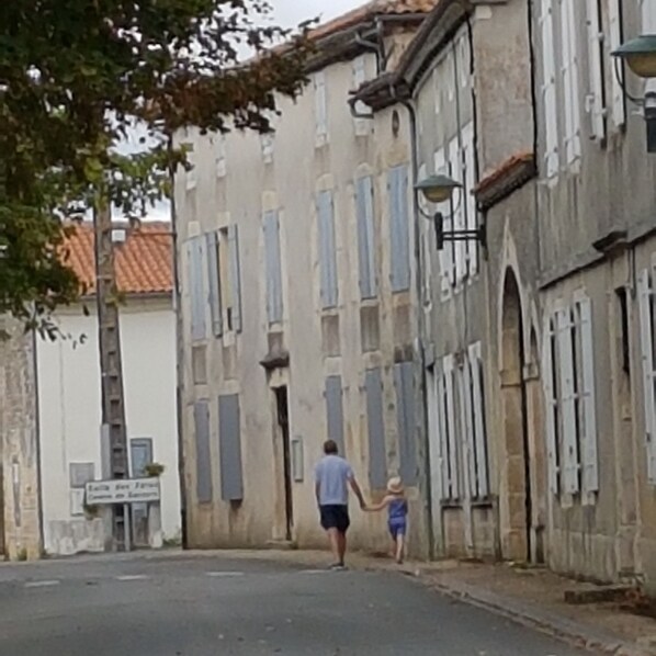 A narrow street with old buildings, a man walking with a child, and a sign that reads "Casa de la Cultura."