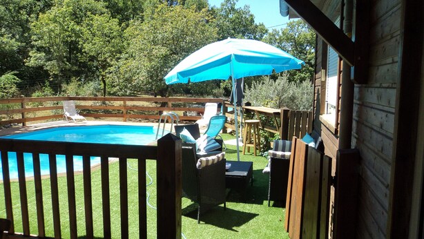 A backyard with a swimming pool, lounge chairs, and a wooden deck. - Timber frame house with garden (Vers)