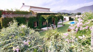 A villa with a swimming pool, lush garden, and mountainous backdrop. - Private Pool & Garden, BBQ, AC, PS4 and Views of the Tramuntana Mountains (Pollença)