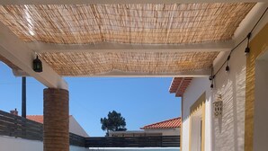 Un área de comedor al aire libre con una piscina al fondo, una mesa dispuesta con diversos platos y una pérgola arriba.