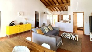 Un espacio habitable amplio con una mesa de comedor de madera, un conjunto de sofás y un armario amarillo brillante.