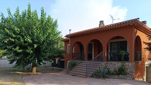 Une maison à deux étages, avec un toit en tuiles, des fondations en pierre et une allée pavée.
