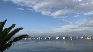 A marina with various boats docked, calm water, and a clear sky.
