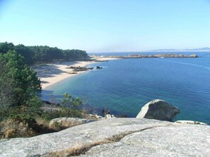 Eine Küstenlandschaft mit klarem, blauem Wasser, Sandstrand und Felsformationen.
