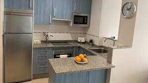 A modern kitchen with blue cabinets, stainless steel appliances, a microwave, a toaster, and a sink.