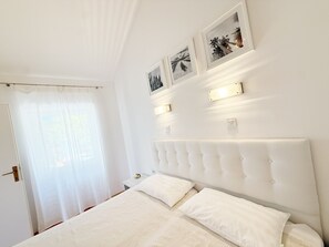 Een slaapkamer met een bed, witte gordijnen en wandlampen.