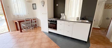 Une cuisine moderne avec un coin repas, comprenant une cuisinière, un évier et une fenêtre avec des rideaux.