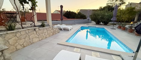 A swimming pool with lounge chairs and a stone wall.