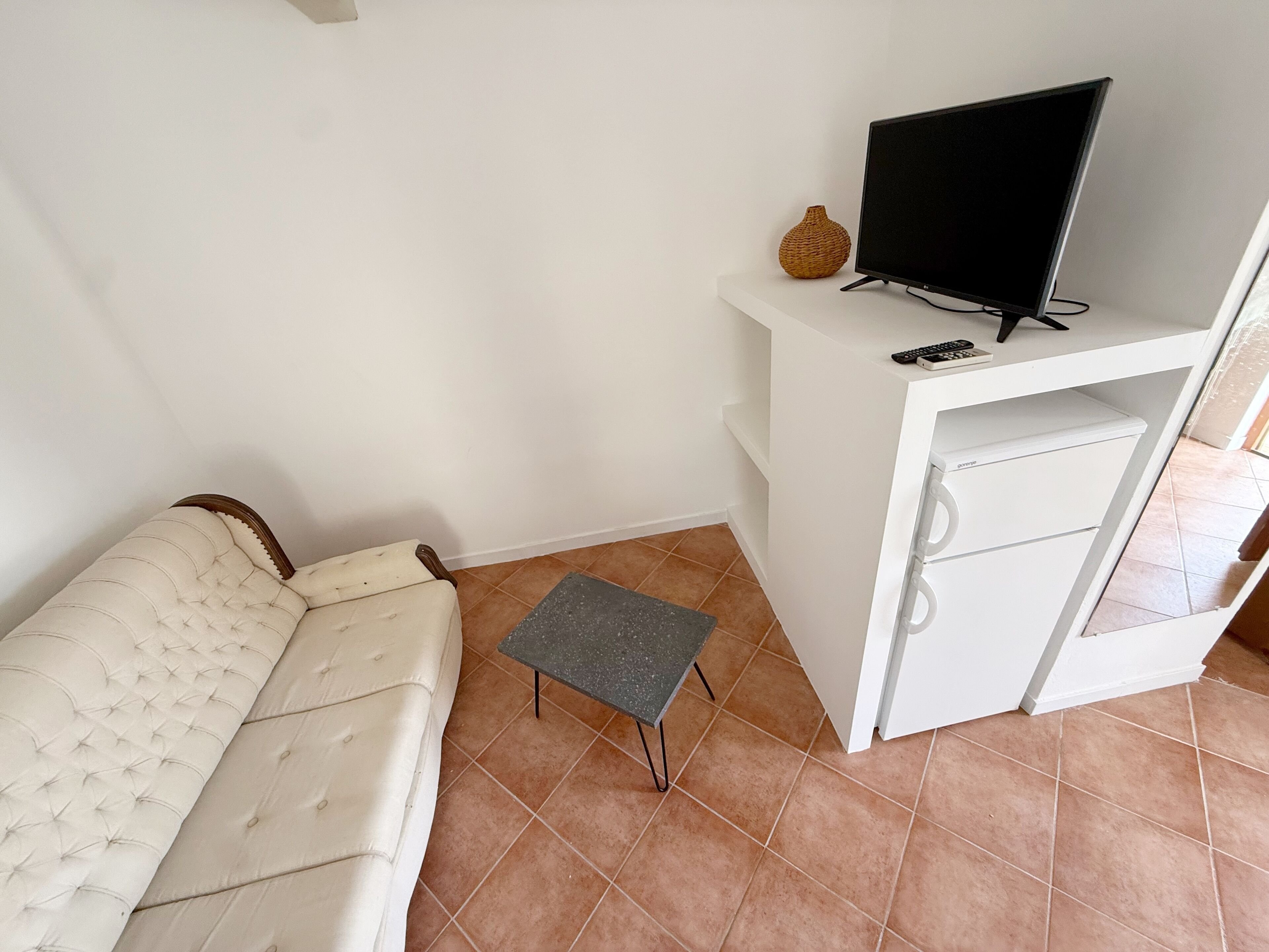 A living room with a sofa, a small table, a TV on a stand, and a cabinet.