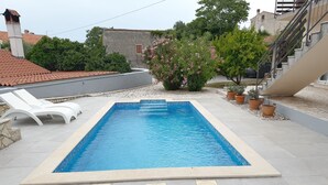 A rectangular swimming pool with a tiled edge, surrounded by white lounge chairs and potted plants. - LacoDeLama mini resort apartment Pina (LIZNJAN)