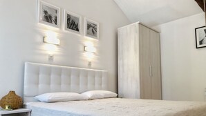 A bedroom with a large bed, a nightstand, a wardrobe, and three framed pictures on the wall. - LacoDeLama mini resort apartment Pina (LIZNJAN)