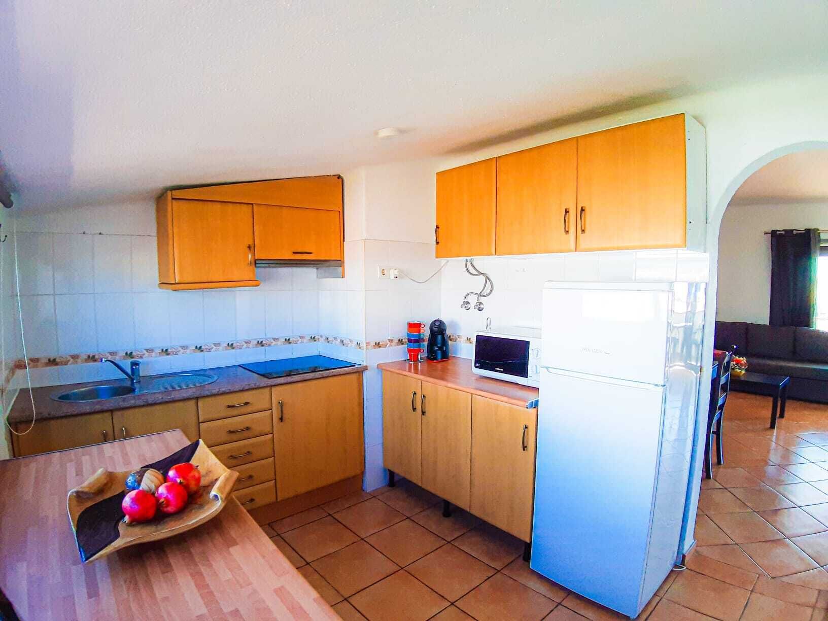 Una cocina compacta con armarios de madera, un microondas y un refrigerador.