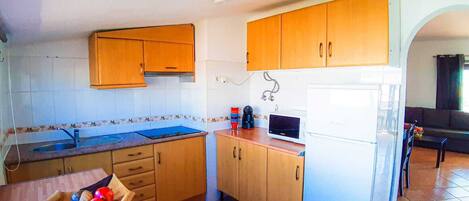 Una cocina compacta con armarios de madera, un microondas y un refrigerador.