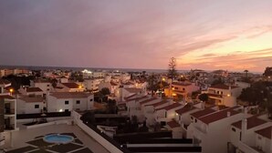 A swimming pool with a view of a coastal town at dusk. - Sea View , Free Wifi, walking distante from the strip (Albufeira)