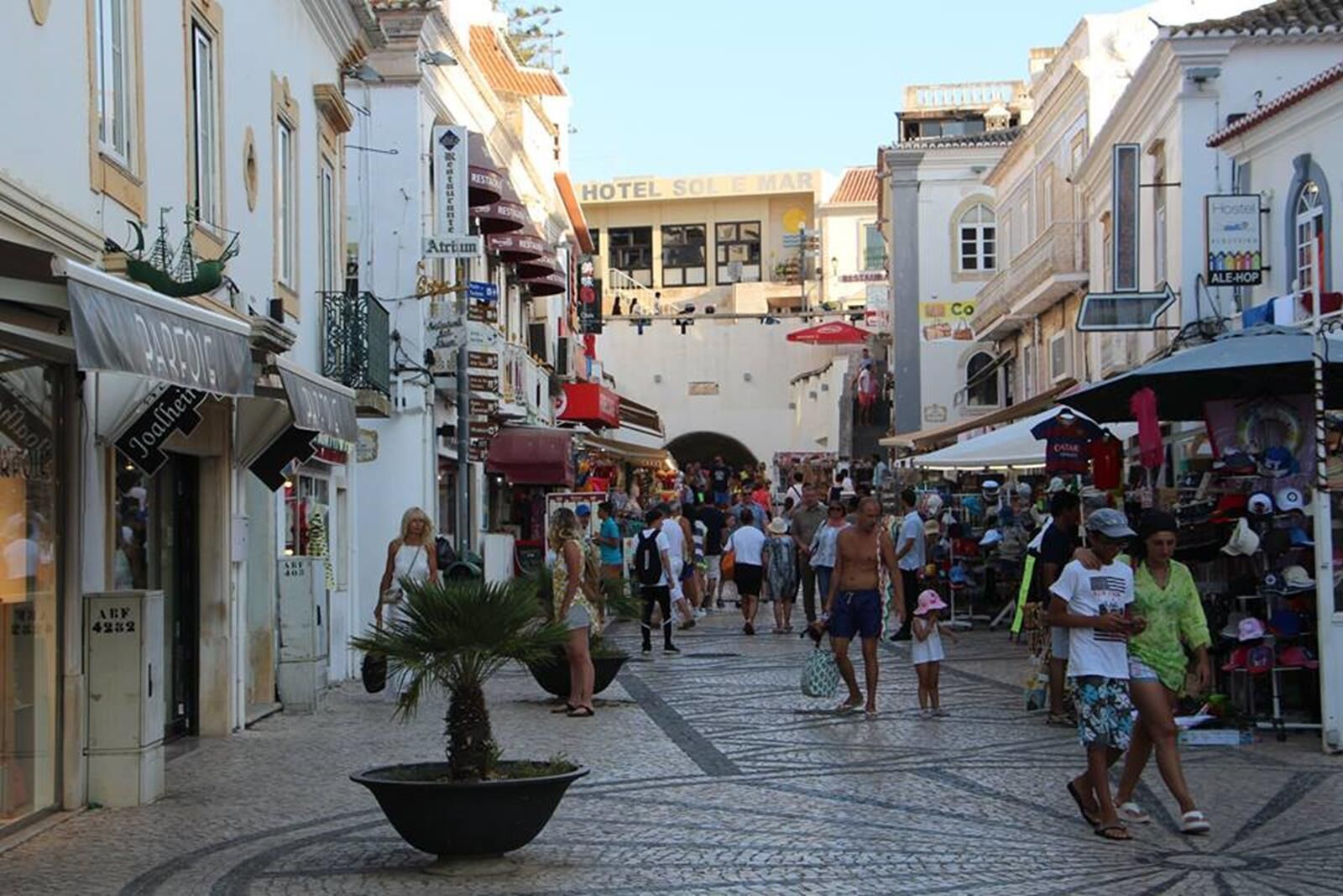Una calle concurrida con tiendas y un hotel llamado 'HOTEL SOL E MAR'.