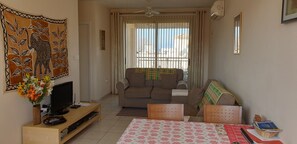 A living room with a sofa, TV, and a table with a patterned tablecloth.