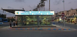 En busshållplats med ett väderskydd, en skylt för Paphos transportorganisation och en skylt som förbjuder parkering.