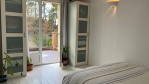 Et soveværelse med en seng, en skydedør til en balkon og en potteplante.