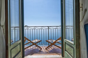 An open balcony with a view of the sea, featuring two wooden chairs and a metal railing. - BIG APARTMENT IN AMALFI WITH ENDLESS SEA VIEW, FAST WIFI, FREE PARKING, A/C (Tovere di Amalfi)