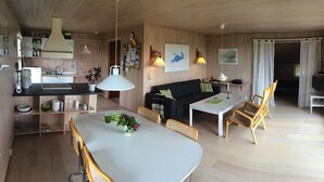 Une cuisine moderne avec un coin repas, un plancher en bois et une grande fenêtre agrémentée de rideaux.