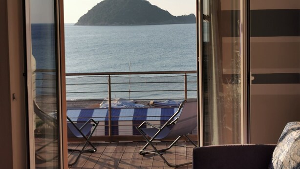 A balcony with two sun loungers and a table, overlooking a calm sea and a small island. - TWO-ROOM APARTMENT NEW SEA VIEW GALLINARA ISLAND DIRECTLY ON THE BEACH (ALBENGA)