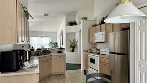 Eine moderne Küche mit Holzschränken, einem Edelstahlkühlschrank, einer Mikrowelle und einer Kaffeemaschine.