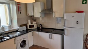 Eine kompakte Küche mit Waschmaschine, Mikrowelle und Kühlschrank.