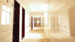 A long, well-lit hallway with a patterned carpet, leading to multiple doors on either side. - Dinghushan Hotel (Zhaoqing)