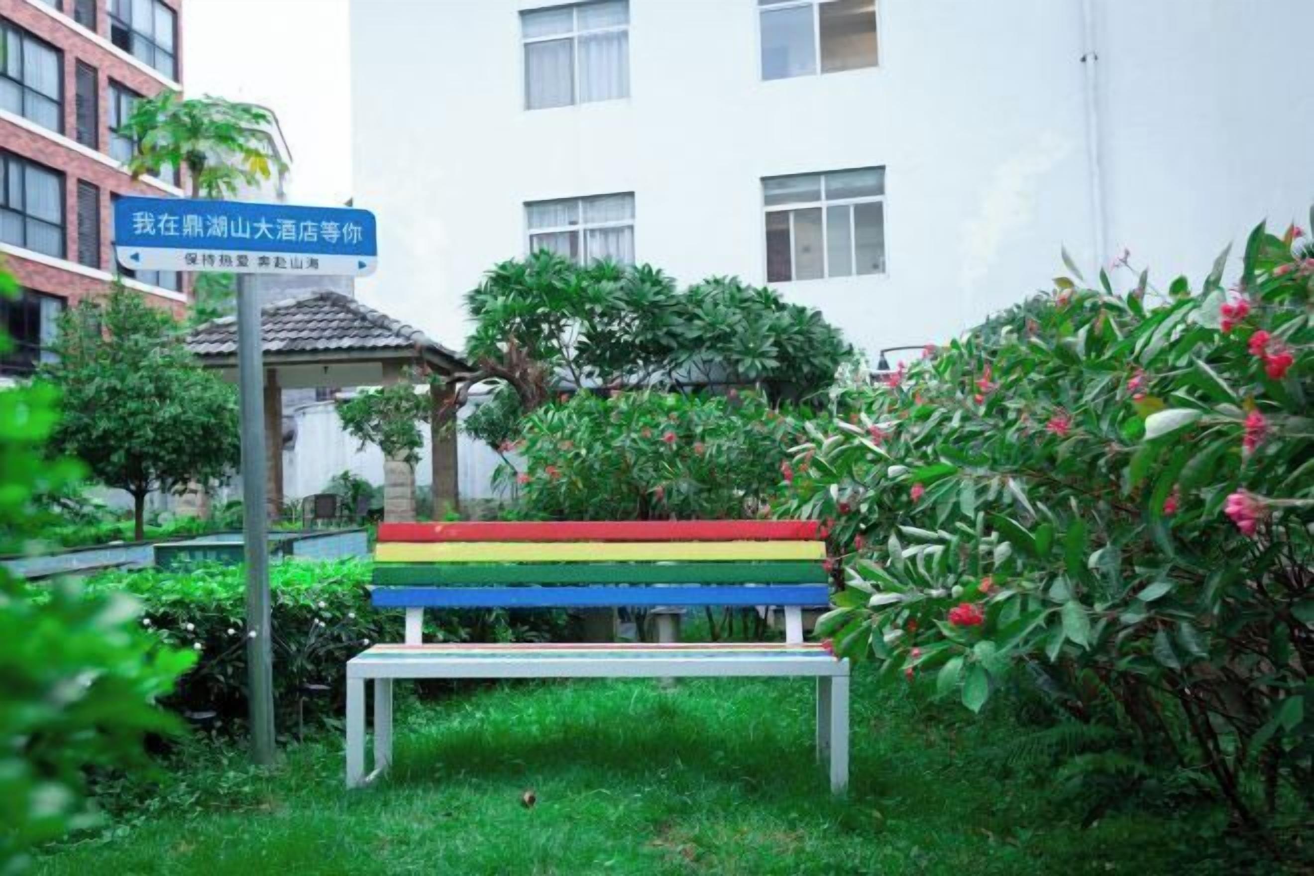 A bench in a garden area with a sign in the background.