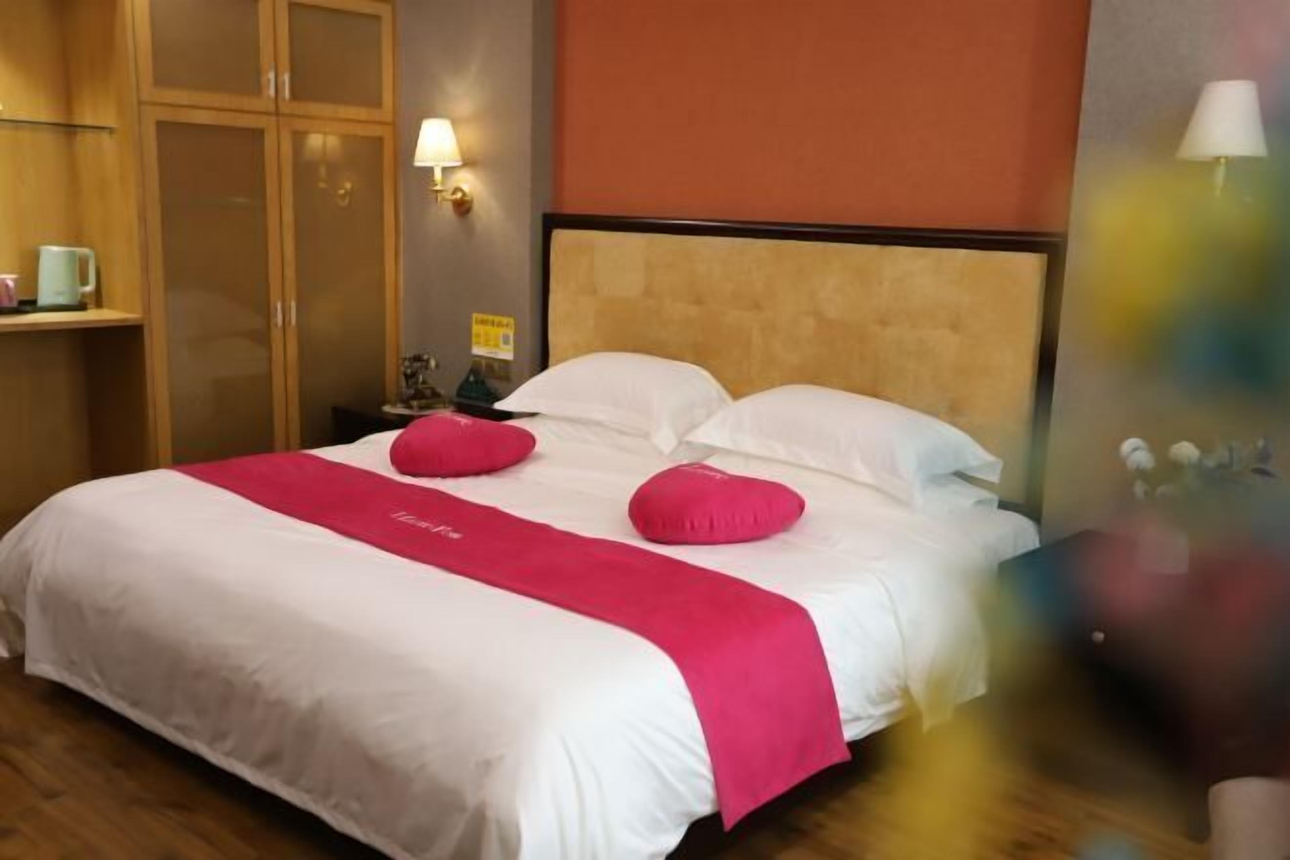 Une chambre d’hôtel avec un lit, une table de chevet, une lampe et une armoire.