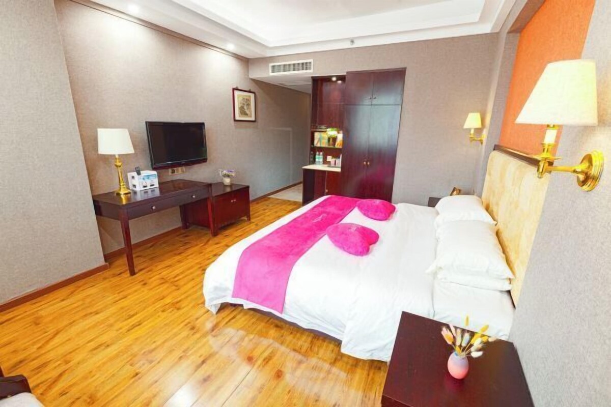 A hotel room with a bed, a desk, a TV, a wardrobe, and a nightstand.