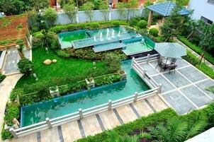 A rooftop swimming pool with a surrounding garden, a seating area, and a pergola.