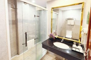 A modern bathroom with a glass-enclosed shower, a black countertop, and a large mirror with a gold frame. - Dinghushan Hotel (Zhaoqing)