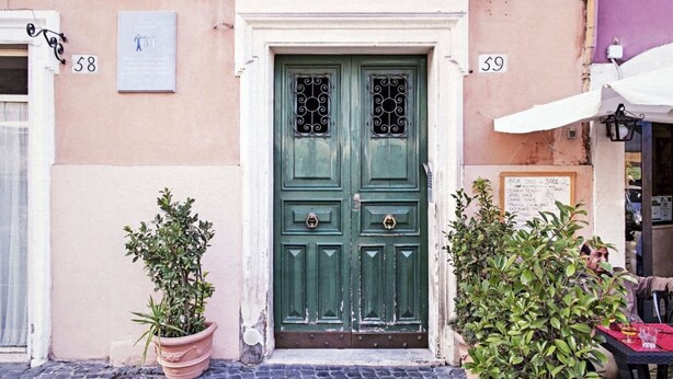 A building with a green double door, numbered 58 and 59, flanked by potted plants. - TrastevereHome - Garibaldi Rome (Roma)