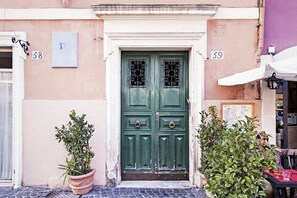 Un edificio con una puerta verde doble, con los números 58 y 59, flanqueado por macetas con plantas.