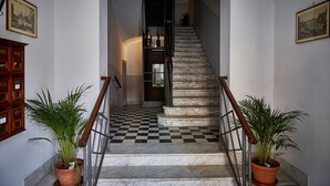 A staircase with a checkered floor, flanked by two potted plants, leading to a dark interior. - TrastevereHome - Garibaldi Rome (Roma)