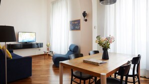 A modern living room with a sofa, a dining table, and a TV. - TrastevereHome - Garibaldi Rome (Roma)