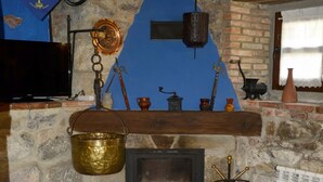 Una habitación rústica con chimenea de piedra, muebles de madera y pared azul.